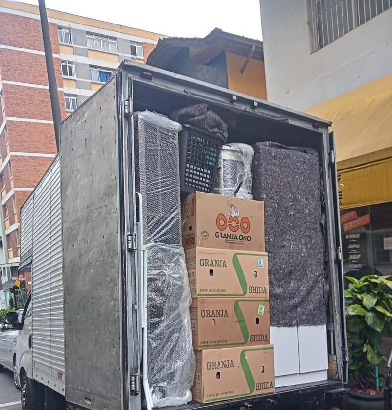 Caminhão de mudança carregado com caixas e móveis protegidos com plástico bolha e manta, em São Paulo