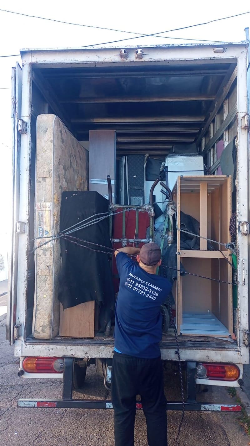 Funcionário da Villa Transportes amarrando móveis no caminhão antes da mudança